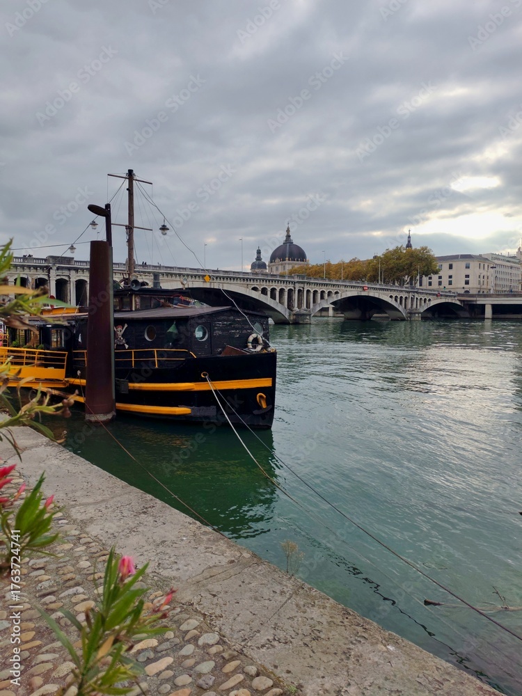 Obraz premium Rone, Lyon, France - October 22, 2025 : A black boat docked on a river Rone 