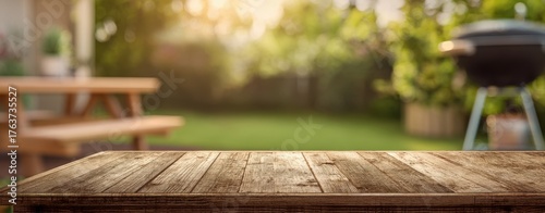 The wooden table in a sunlit backyard with picnic bench and barbecue grill