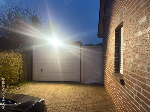 Ein heller Strahler leuchtet am Abend die Einfahrt zu einer Garage aus