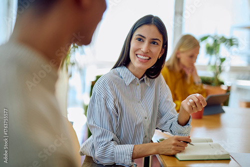Tableau sur toile Young businesswoman smiling, listening, and engaging in conversation with a coll