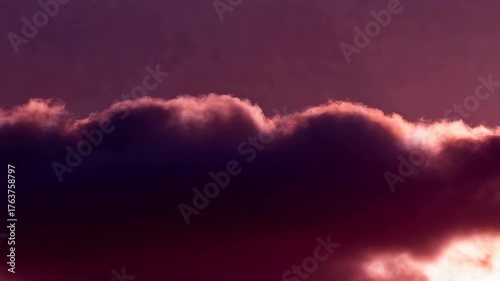 Dramatic Sunset Clouds Painted In Vivid Purple and Orange Hues With Soft Golden Light Edging the Tops Awaiting Nightfall