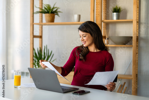 Successful happy professional business woman working on her laptop in a bright home office