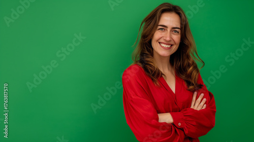 Mulher sorridente com braços cruzados em blusa vermelha e fundo verde