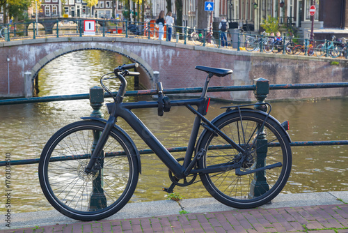 Canvas Print Modern electric bicycle parked by a scenic canal in Amsterdam