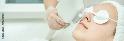 Young caucasian female receiving laser facial treatment at spa for skin rejuvenation.