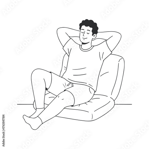 A relaxed young man sitting comfortably on a soft chair enjoying a peaceful moment at home