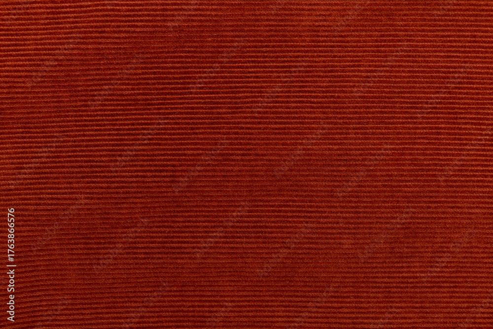 Fototapeta premium Detailed texture of a corduroy fabric in a rich burnt orange, red tone