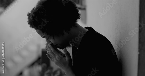 Obraz na plátne African American boy leaning against a wall, covering his face with hands, overw