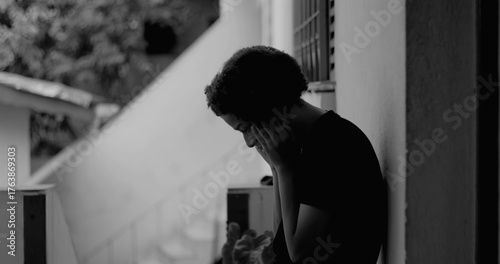Photography African American boy standing alone by a wall, head bowed in sadness and despair