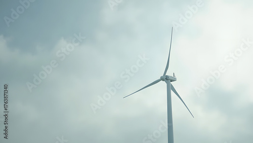 Minimal wind turbine icon on a cloudy background, isolated with left-side copyspace. Symbolizing renewable energy and sustainability.