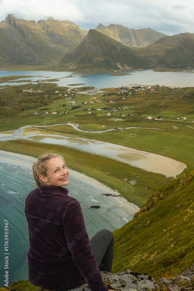 Fototapeta premium Young beautiful woman resting at a hill with beach and lakes in the background