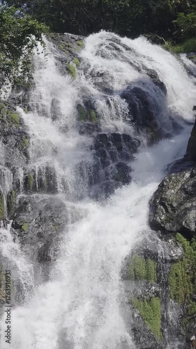 Majestic Waterfall Cascading Over Rocky Terrain in Lush Green Environment