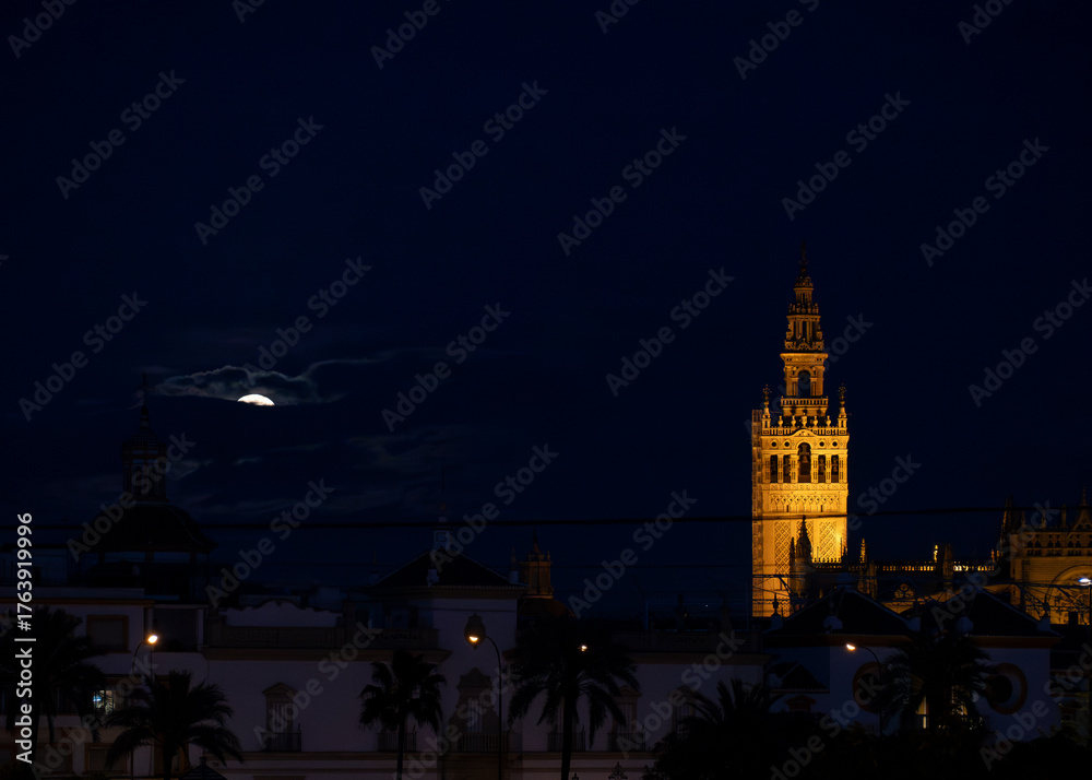 Fototapeta premium Seville, Spain - February 24, 2024. The Giralda Tower of Seville illuminated under the moonlight on an Andalusian night