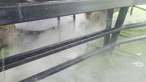 Mist Rising from the Ground Under a Metal Structure Surrounded by Lush Greenery in Nature