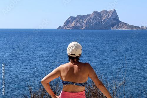 Woman from behind in a bikini looking at the sea. Vacation, retirement. 