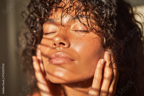Woman Enjoying Sunlight While Gently Touching Her Face in a Cozy Indoor Setting