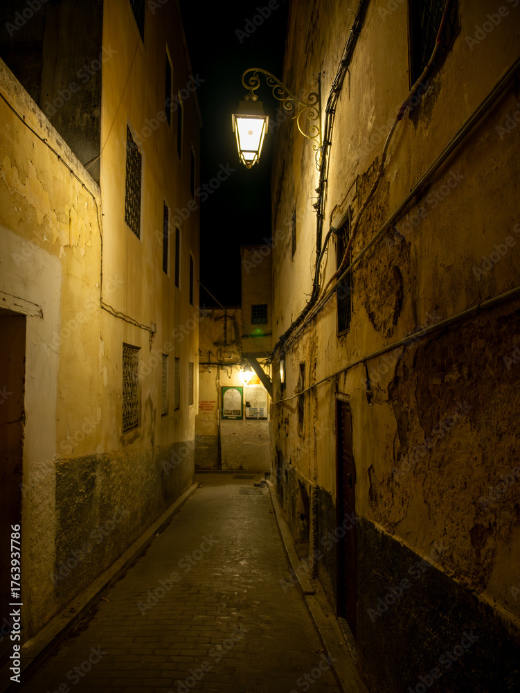 Fototapeta premium A small dark residential street in the medina of Fes, at night