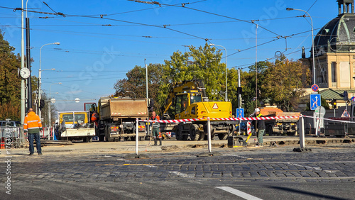 Roadworks in the city – road repairs with an excavator and workers in high-visibility vests