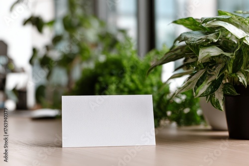 Blank Card Placed on a Wooden Table Surrounded by Green Plants in a Bright Room