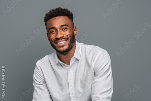 Smiling Man in a Light Shirt Poses Against a Neutral Background During a Phot...
