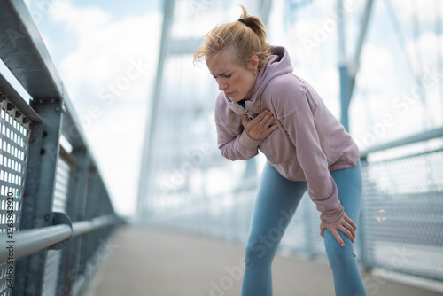 Schilderij op canvas Woman experiencing chest pain while running on bridge