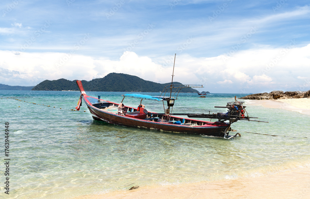 Fototapeta premium Traditional Thai longtail boats anchored on tropical beach with clear water and island landscape. 
