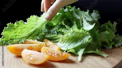 Close-up of tomatoes and lettuce on a wooden board on a black background. Concept of healthy eating and organic farm products. Slow motion 100 hp.