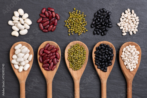Beans selection in  spoons on black background, top view