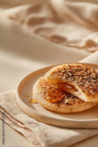 Delicious korean hotteok pancakes drizzled with syrup and sprinkled with sesame seeds served on a plate with a beige cloth