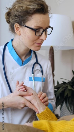 Caring female doctor visiting an elderly patient at home, holding her hand and carefully checking the pulse on her wrist, providing support and medical care during a home healthcare visit