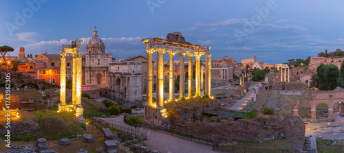 Ancient Roman Forum with lit columns and ruins at sunset in Rome, Italy