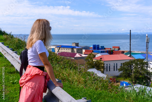 Woman gazing at the coastal town while overlooking the ocean on a sunny day