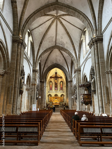 Carta da parati The photo shows the grand altar of Osnabruk’s Romanesque cathedral, featuring high vaulted ceilings, stained glass windows, and an illuminated golden altarpiece
