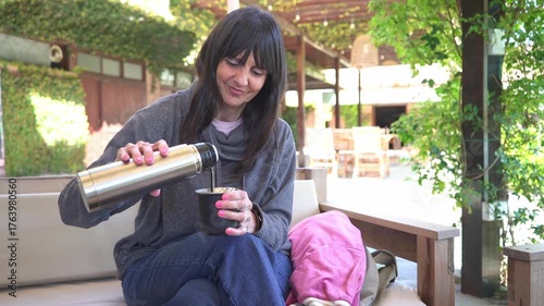 Woman preparing and serving traditional yerba mate outdoors on a sunny terrace