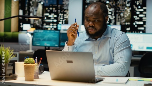Photos Black general manager envisioning a tactical solution and playing with pen, working late alone in office