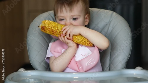 A little girl eats an ear of corn with gusto.
