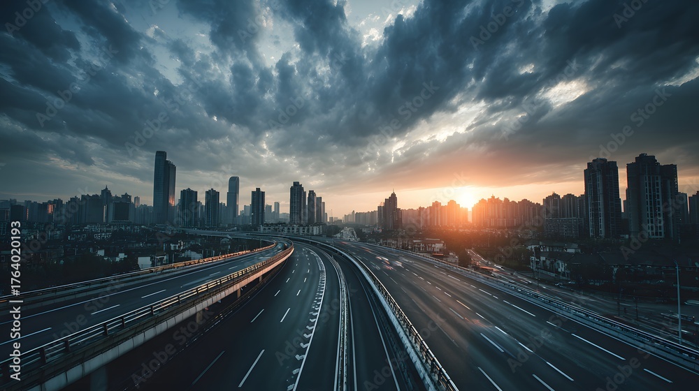 Fototapeta premium Elevated highway curves through a metropolitan area during a dramatic sunset with heavy cloud cover