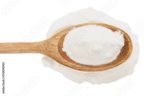 Close-up of baking soda in rustic wooden spoon on white background