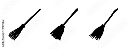 Three black rustic witch broomsticks flying in a line with textured bristles and handles