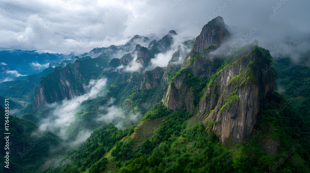 Fototapeta premium Majestic cliffs rise above green valleys in Enshi City, Hubei Province, with clouds swirling around rugged mountain peaks under a vast sky, showcasing natural beauty and dramatic landscapes.