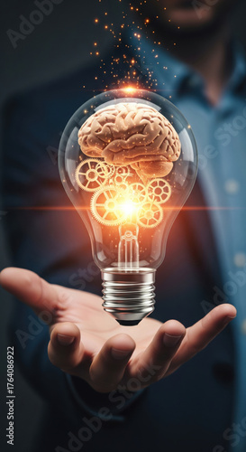 Human hand holding glowing light bulb with brain and gears inside, symbolizing creativity, innovation, intelligence, and inspiration in business setting