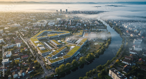 Aerial cityscape view of modern buildings and a river under morning fog in Europe