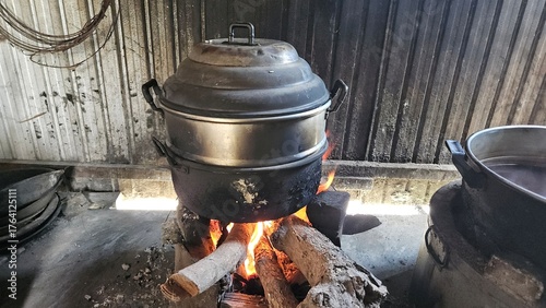 Traditional Vietnamese cooking scene with a large pot steaming over a wood fire stove, used to boil traditional cakes during festive or family gatherings in rural Vietnam.