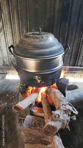 Traditional Vietnamese cooking scene with a large pot steaming over a wood fire stove, used to boil traditional cakes during festive or family gatherings in rural Vietnam.