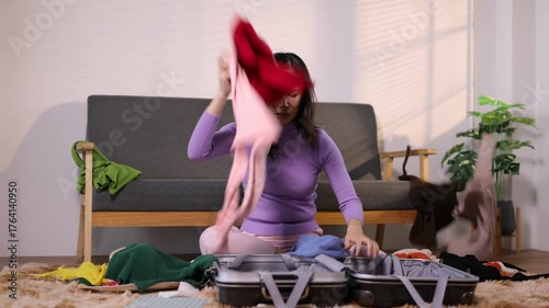Frustrated woman throwing clothes while packing suitcase. A young woman is disappointed that her travel trip failed.