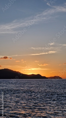 Stunning ocean sunset with vibrant orange hues reflecting on the water and distant islands, perfect for travel and relaxation themes