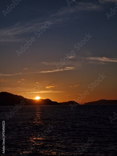 Stunning sunset over the ocean with silhouetted islands, evoking feelings of tranquility, escape, and the beauty of nature's serene moments