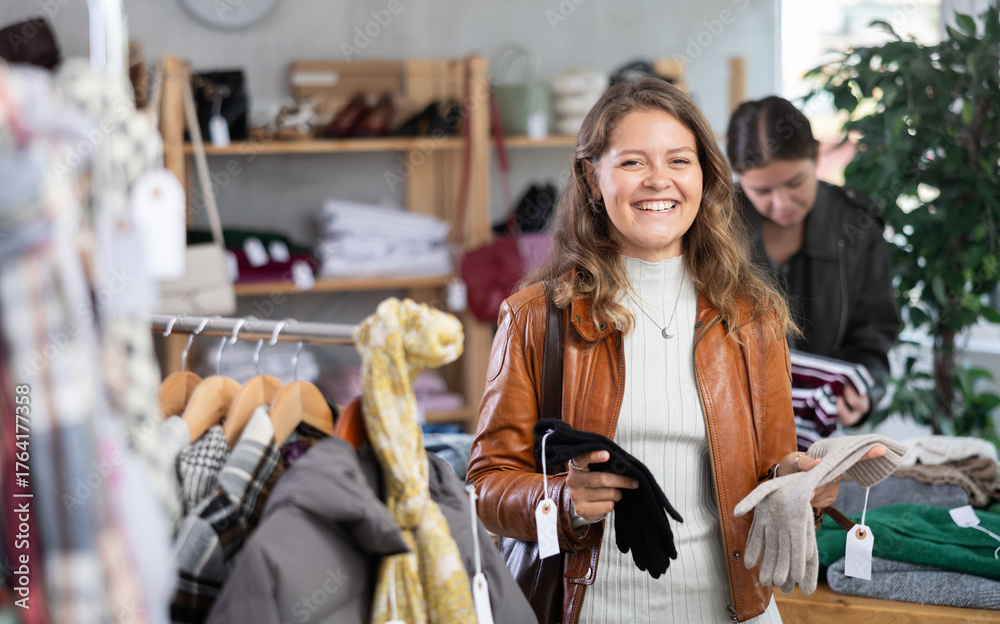 Fototapeta premium Girl carefully selects warm winter gloves in a clothing store