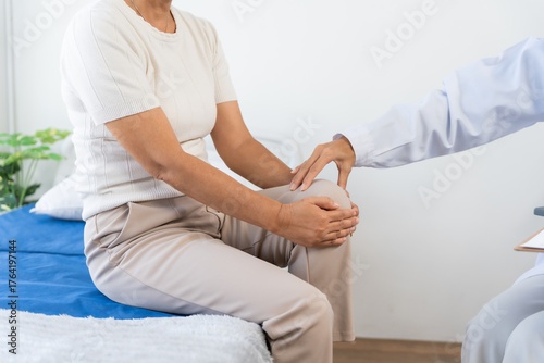Doctor examines senior woman's knee in clinic, assessing joint pain and arthritis during medical consultation and physical exam