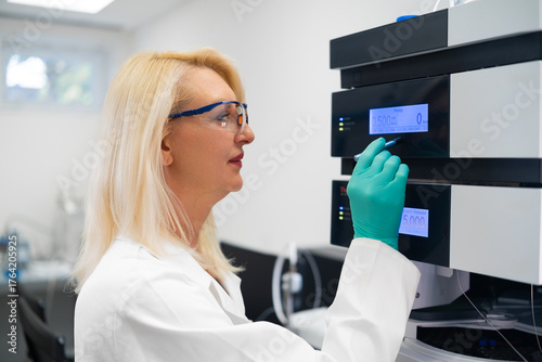 Female researcher setting up liquid chromatography equipment for clinical and drug analysis.